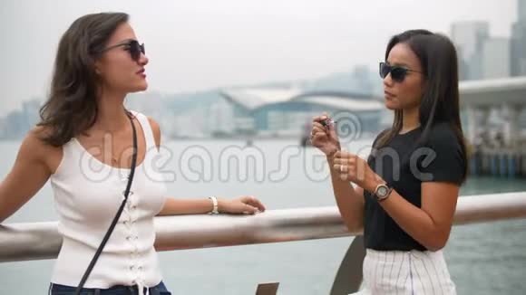 漂亮的年轻亚洲女人用朋友的太阳镜涂口红视频的预览图