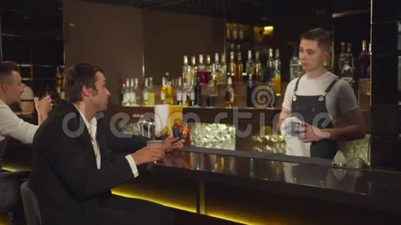 男人坐在酒吧和酒保说话对某人微笑视频的预览图