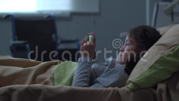 小女孩躺在医院的床上打电话视频的预览图