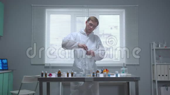 前面看穿防护工作服的人从实验室的管子里取出化学物质视频的预览图