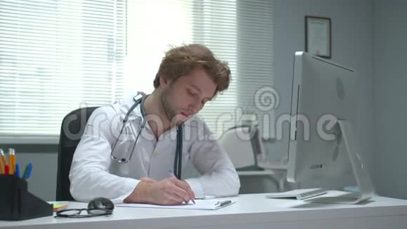 医生坐在医院的一张桌子旁写着视频的预览图