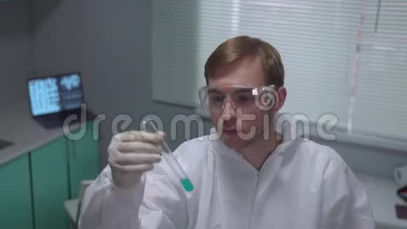 在实验室里用蓝色液体的保护工作服摇管中的化验员视频的预览图