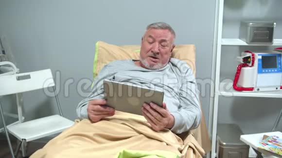 男人躺在床上和某人在平板电脑上交谈挥动他的手视频的预览图