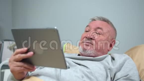 男人躺在医院的床上和某人在药片上交谈视频的预览图