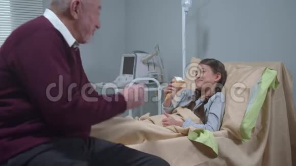 女孩躺在床上吃冰淇淋和她的祖父说话视频的预览图