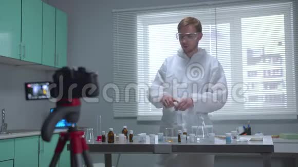 穿着防护服的人在实验室里用照相机把液体倒入管子里视频的预览图
