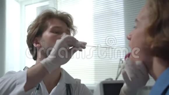 医生在医院的柜子里用棍子检查男孩的喉咙侧视视频的预览图