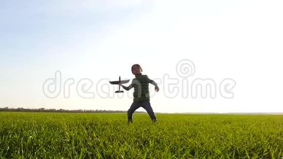 一个小男孩玩飞机穿过一片绿色的草地把它发射到天空中快乐的孩子视频的预览图