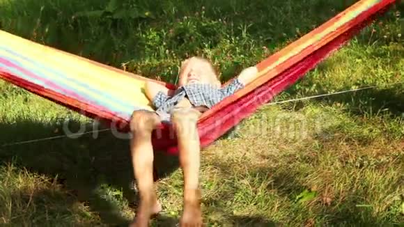 小男孩微笑着在吊床上享受阳光视频的预览图