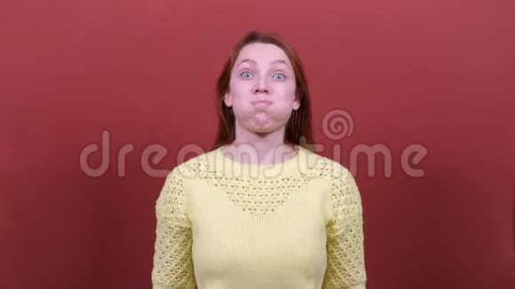 红头发的年轻女子看着镜头膨胀脸颊人真诚的情感生活方式的观念视频的预览图