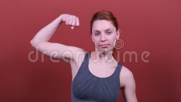 一位年轻的运动女子红发炫耀她的二头肌体育运动很好视频的预览图