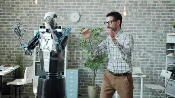 快乐的上班族在工作中和机器人跳舞享受休息视频的预览图