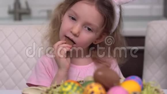 复活节快乐巧克力蛋一个兔子耳朵里的小女孩从复活节彩蛋后面出现家庭幸福子女视频的预览图