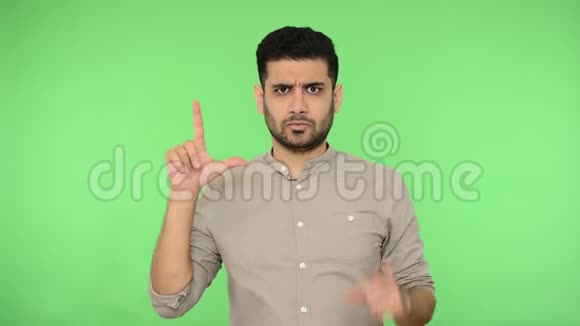 愤怒的黑发男子显示失败者的手势我用手指和指向相机签名绿色背景色度键视频的预览图