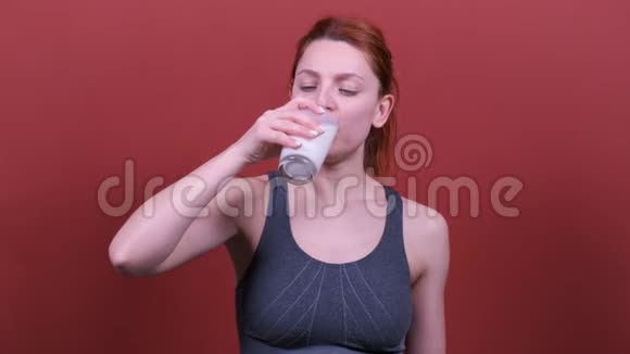 红色头发的年轻健身女人喝牛奶人真诚的情感生活方式的观念视频的预览图