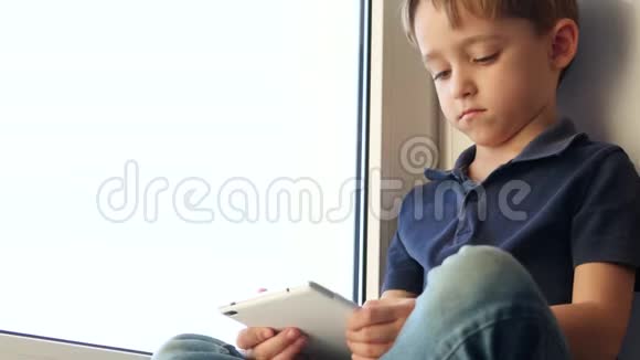 孩子用平板电脑坐在窗口儿童和技术视频的预览图