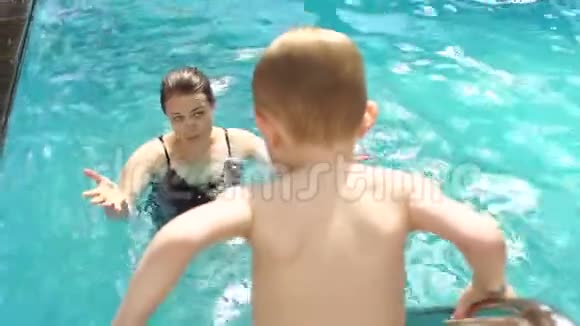 母子俩在水池里游泳孩子在楼梯上爬进水里视频的预览图
