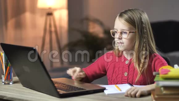 可爱的小女孩用笔记本电脑在家学习视频的预览图