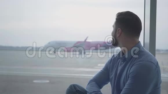 侧视特写的俊脸胡子男看着飞机起飞年轻的白人坐在视频的预览图