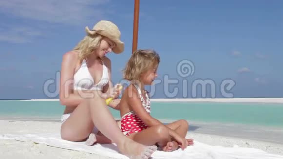 母亲以阳光保护女儿海滩假日视频的预览图