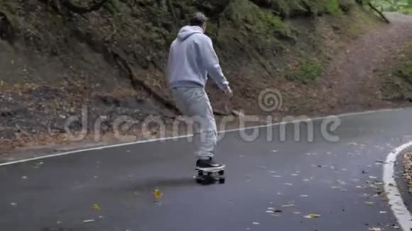 滑板运动员骑着滑板在蜿蜒的山路上旋转视频的预览图