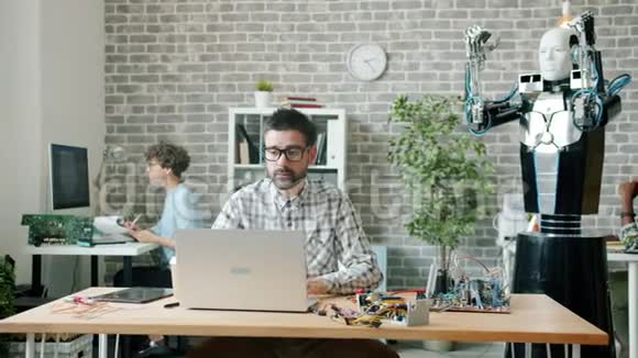 机器人工程师用电线和笔记本电脑建造和测试办公机器人视频的预览图