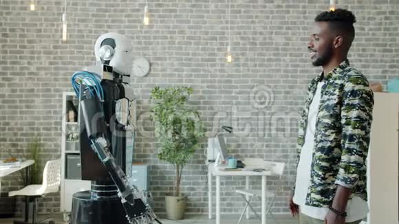 快乐的非裔美国人和像男人一样的机器人握手视频的预览图