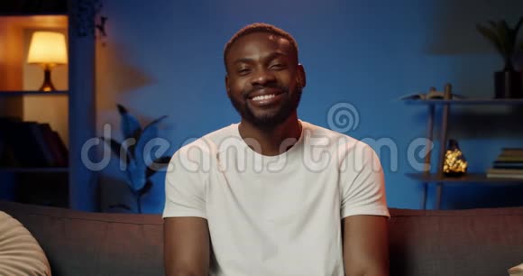幸福的人穿着白色t恤微笑着看着镜头的肖像心情好的非洲帅哥的正面景色视频的预览图