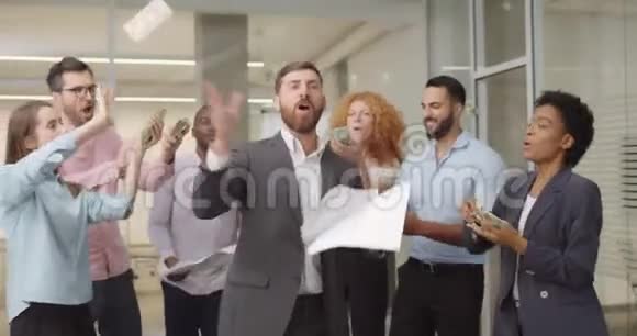 男女办公室工作人员在空地上用金钱和文件跳舞兴奋的商业团队扔掉美元视频的预览图
