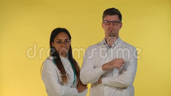 穿着实验室外套和眼镜的不同医生否认有黄色背景的东西视频的预览图