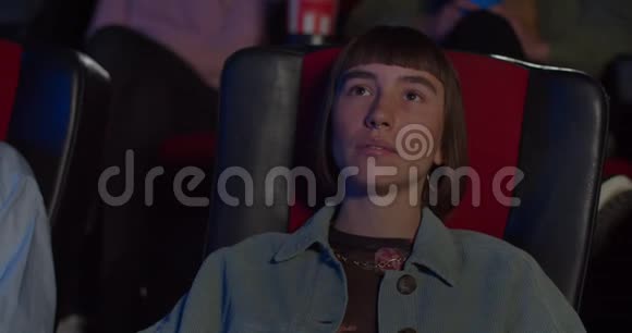 嬉皮士女孩在电影院看动作片年轻女子大眼睛张开嘴在电影里说哇视频的预览图