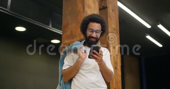 在使用智能手机时戴眼镜的帅哥笑了穿着便装的胡子男视频的预览图