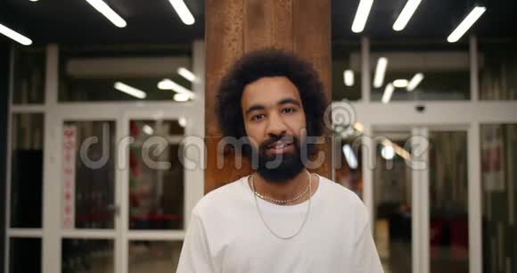 一幅穿着白色t恤的开朗男人看着镜头微笑的肖像三十岁的大胡子站在现代社会视频的预览图
