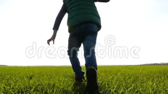 一个快乐的孩子跑过一片绿色的草地手里拿着一架飞机飞向天空相机跟着一个视频的预览图