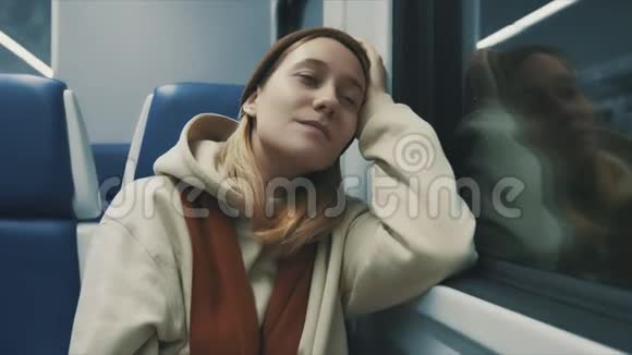 火车上迷人的微笑女孩的肖像窗外看着年轻的慢动作视频的预览图