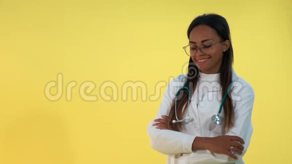黄色背景下非洲女医生对着镜头微笑的肖像视频的预览图