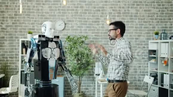 快乐的开发商跳舞与智能机器人享受工作乐趣视频的预览图