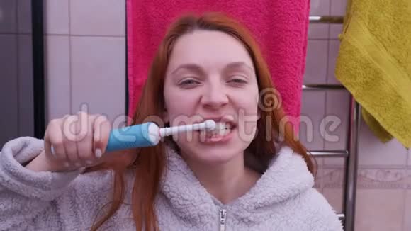 浴室里用电动牙刷刷牙的女人视频的预览图