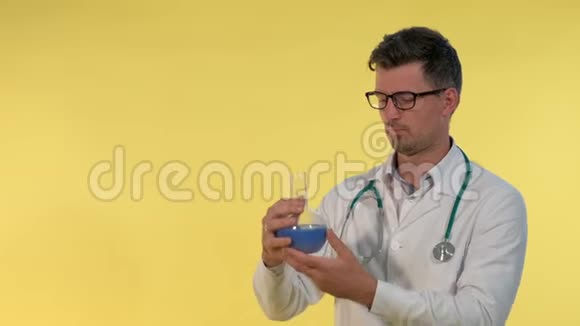 年轻医生的特写穿着实验室外套戴着眼镜用蓝色液体望着瓶子视频的预览图