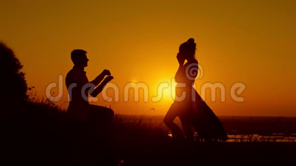 一个女孩和一个男人男孩跪在膝盖上在夏天的草地上向女人求婚夫妻订婚了视频的预览图