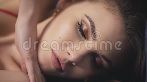 化妆效果肖像特写女士躺着触摸面部化妆眼睛蓬松的长睫毛虹膜纯洁的皮肤激情的感官唇视频的预览图