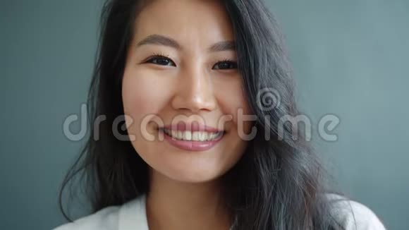 一幅漂亮的亚洲女士在灰色背景下微笑的特写肖像视频的预览图