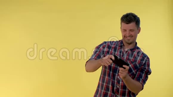 穿格子衬衫的帅哥在智能手机上玩网络游戏视频的预览图