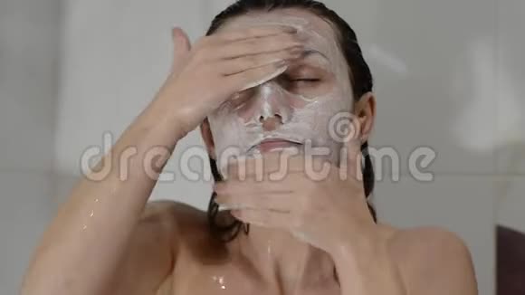 年轻迷人的性感女孩在浴室里做一个白色的擦洗面具视频的预览图