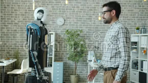 年轻的男性开发者和人形机器人半机人站在办公室握手视频的预览图
