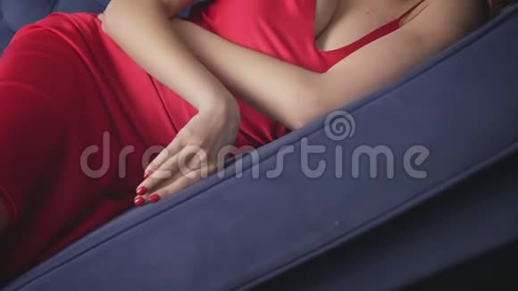 性感的女人躺在沙发上穿着红色丝绸连衣裙摸着脸手化妆眼睛毛茸茸的长睫毛纯洁的皮肤激情性感的Li视频的预览图