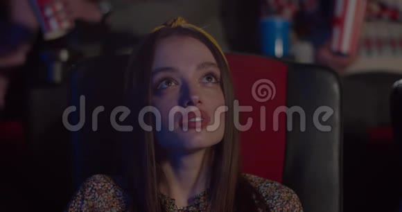 在电影院里坐在椅子上看有趣的电影把年轻女子的脸收起来电影院里的美女视频的预览图