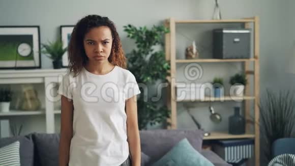 一幅沮丧和愤怒的非洲裔美国女士双臂交叉站在家中的肖像的脸皱着眉头视频的预览图