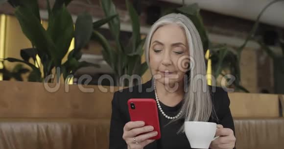 在工作休息期间老时尚女商人坐在现代咖啡馆的桌子前成熟成功的女老板视频的预览图