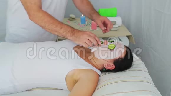 一位男性美容师把新鲜黄瓜放在水疗沙龙客户脸上视频的预览图